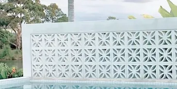 A pool with a white wall and palm trees in the background.