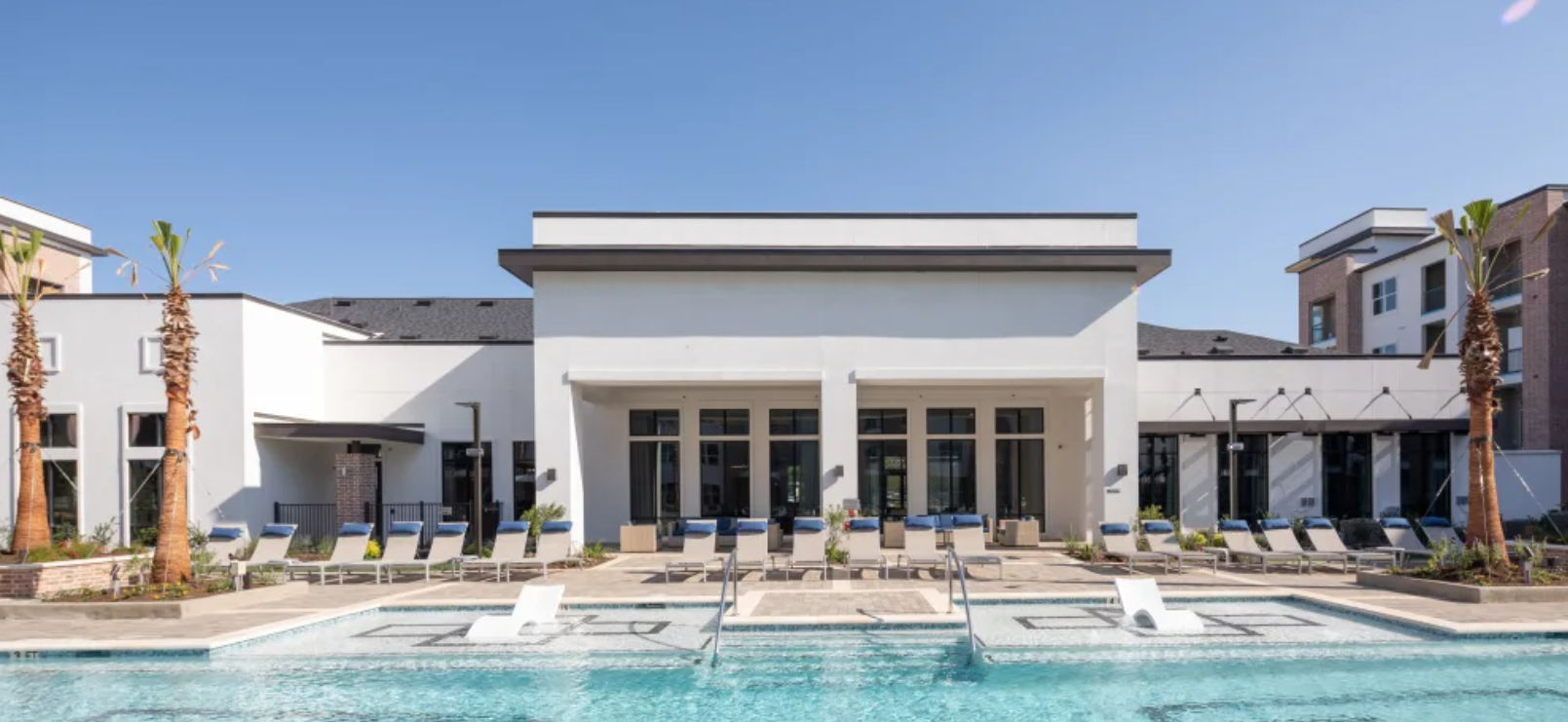 A large pool with chairs and tables in front of it.