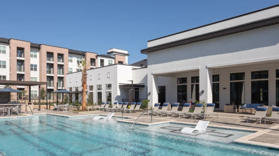 A pool with chairs and umbrellas in the background.