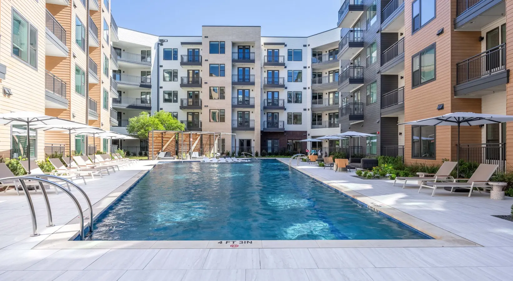 A large swimming pool in front of an apartment building.